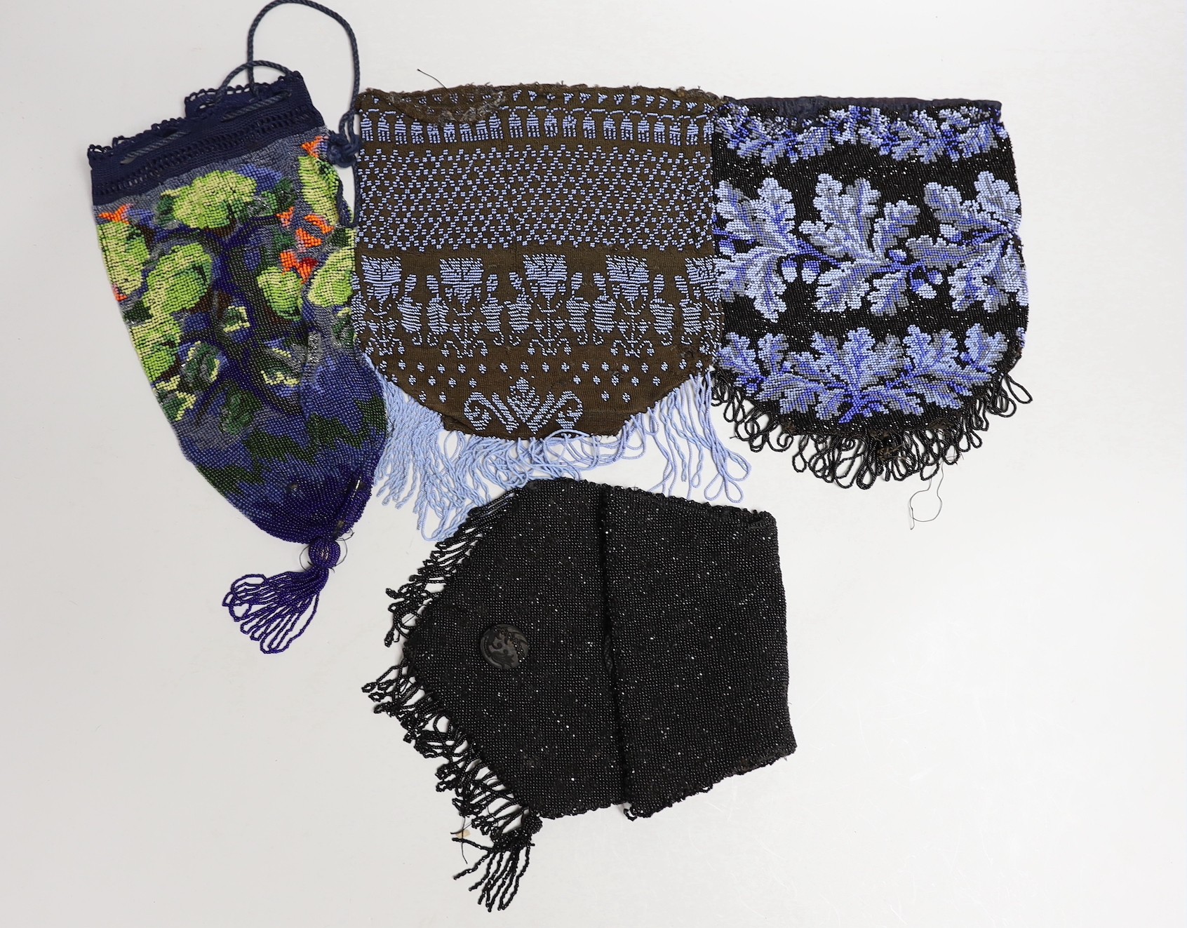 A mid 19th century finely knitted blue beaded bag, another similar later 19th century bag, a multicoloured floral bag with bead tassel to base and a 1930’s black beaded bag (4)